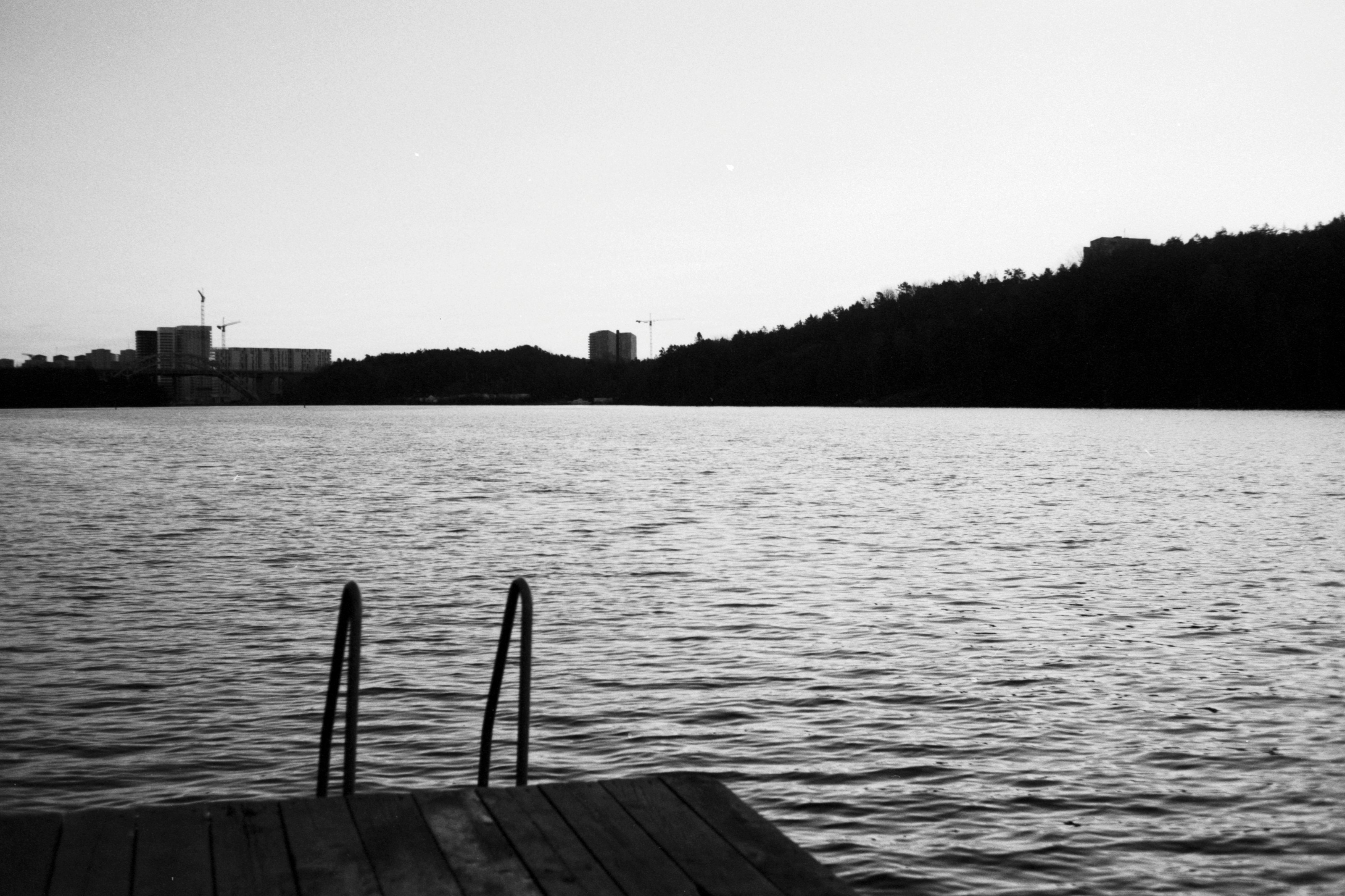 grayscale photo of wooden dock on body of water